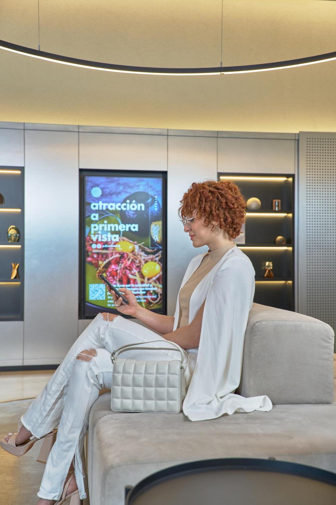 Pullman Santiago Vitacura Exterior photo A woman using a mobile phone to interact with a digital signage display